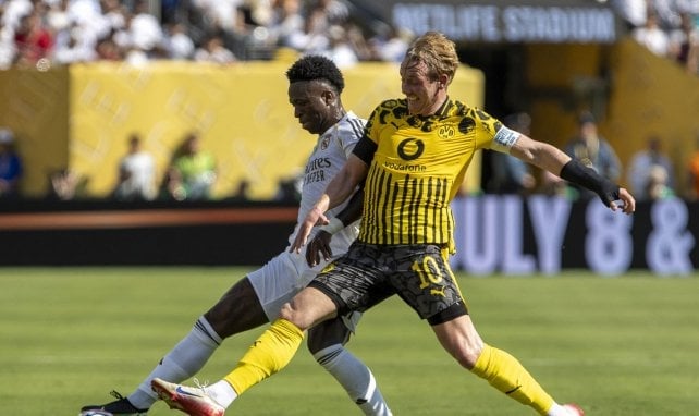Julian Brandt trata de robar el balón a Vinicius Júnior